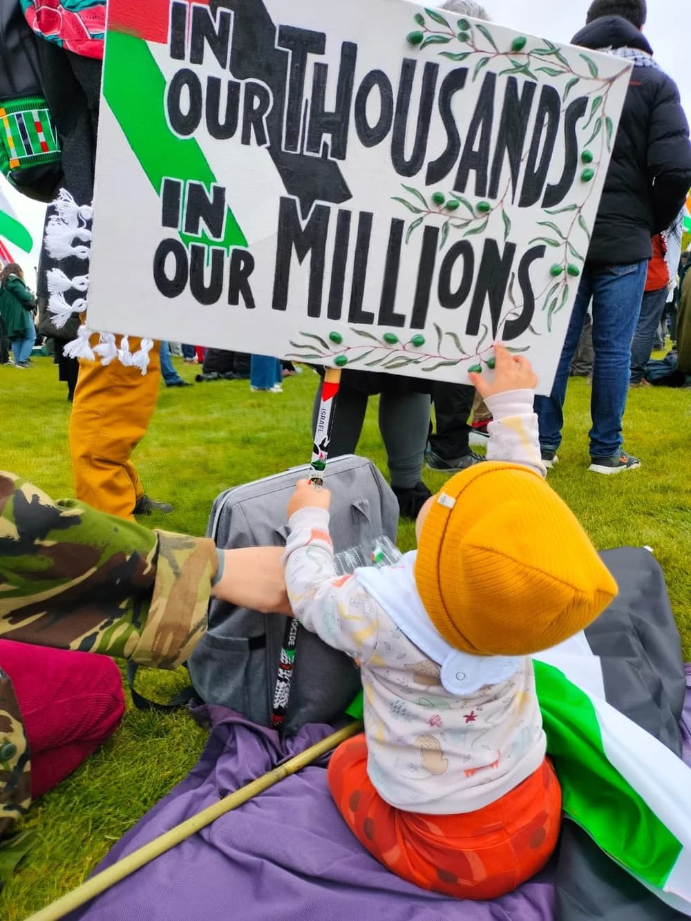 Child facing an In Our Thousands In Our Millions banner